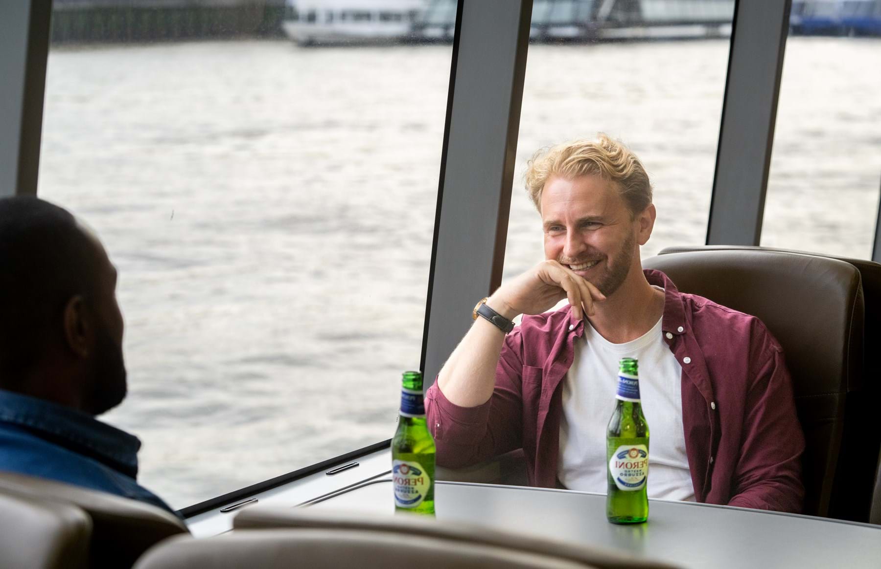 Two male friends drinking beer on board