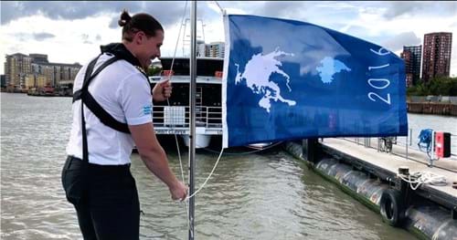 A member of the Uber Boat by Thames Clippers crew hoists a blue flag